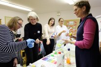 Vier Frauen experimentieren mit Schutzhandschuhen und pH-Streifen.