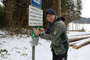 Ein Förster klebt eine grüne Folie auf ein Schild