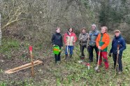 Menschen mit Spaten neben einem eingegrabenen Holztrog