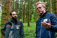 Zwei Männer, stehen im Wald und unterhalten sich.