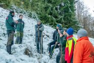 Eine Gruppe Männer steht an einem Berghang im Schnee und unterhält sich.