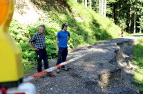 Zwei Männer stehen an einem abgesperrten Weg, an dem ein Teil abgerutscht ist.